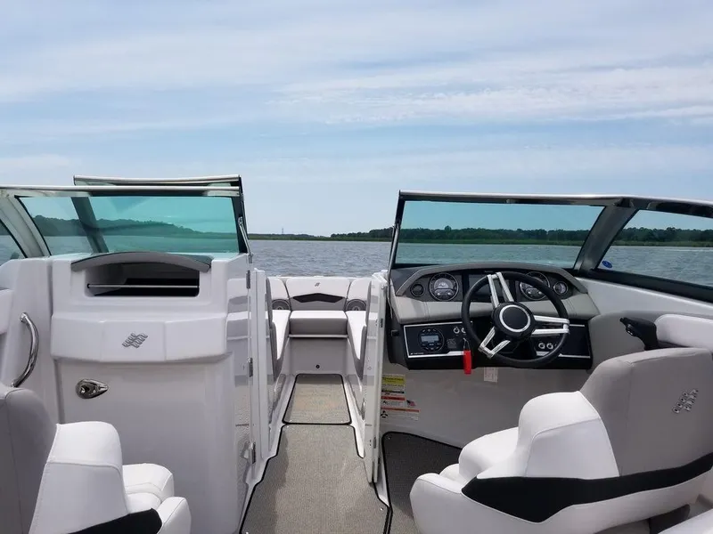 Slide: The Image of 2017 Four Winns H260 boat interior with steering wheel, dashboard, and seating on a calm lake. - 1