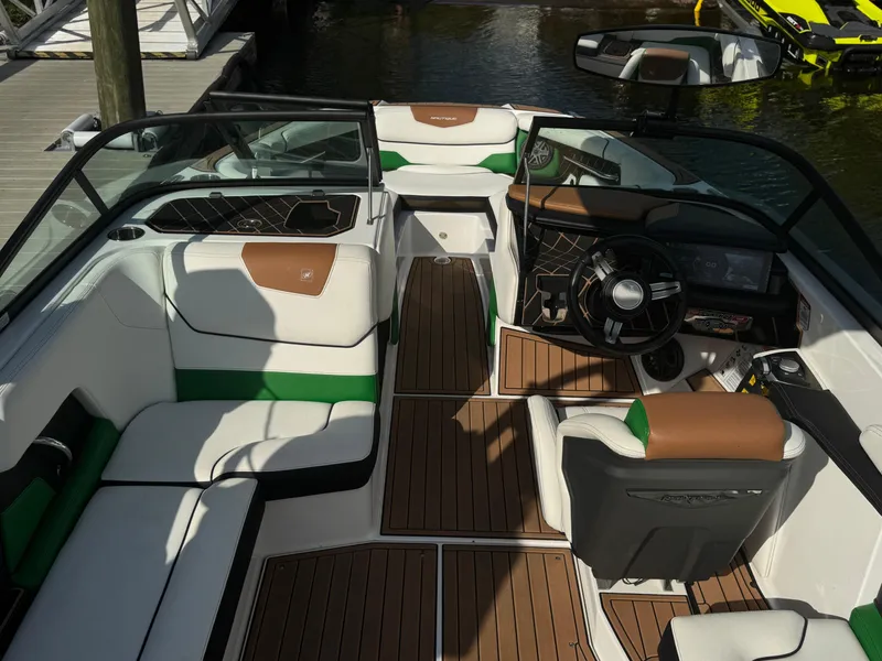 Slide: The Image of 2017 Nautique Super Air Nautique GS20 interior with white, green, and brown seating, docked by water. - 4