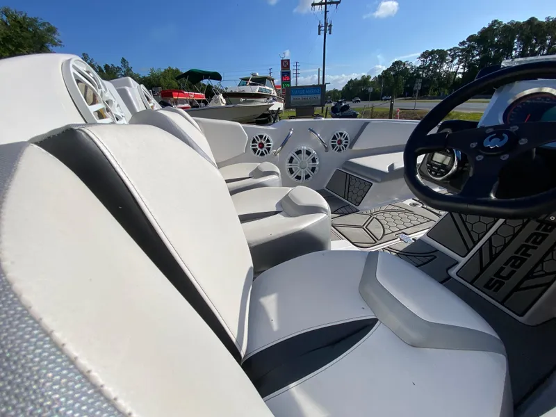 Slide: The Image of Interior of 2018 Scarab 165 boat with white seating and steering wheel, outdoors. - 11