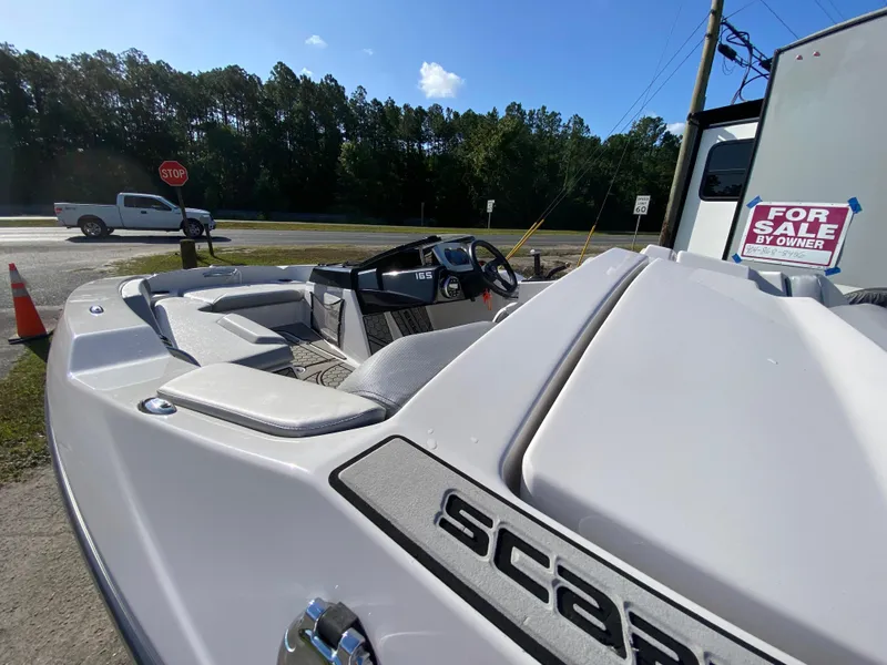 Slide: The Image of 2018 Scarab 165 boat for sale, parked outdoors with a "For Sale by Owner" sign. - 6
