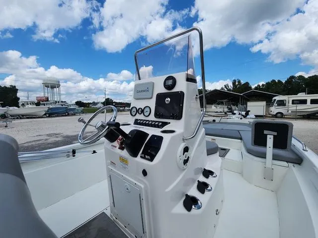 Slide: The Image of 2021 Avid 21 FS boat console with steering wheel and controls under a blue sky. - 21