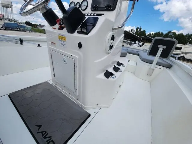 Slide: The Image of 2021 Avid 21 FS boat interior with steering console and seating, under a clear blue sky. - 24