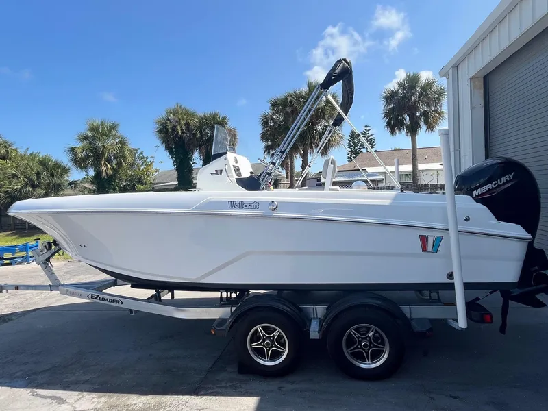 The Image of 2022 Wellcraft 202 Fisherman boat on trailer, parked outdoors near palm trees. - 0