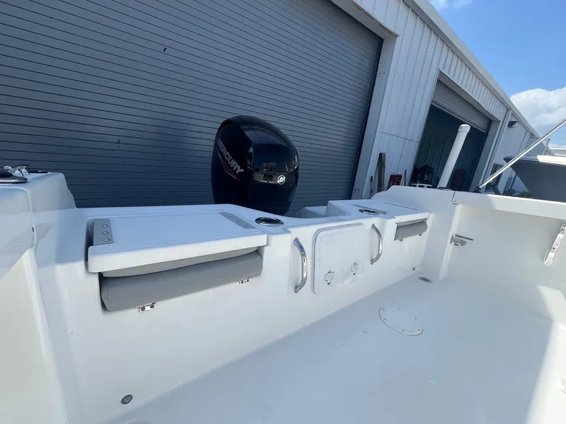 Slide: The Image of 2022 Wellcraft 202 Fisherman boat interior with outboard motor, docked near a garage. - 11