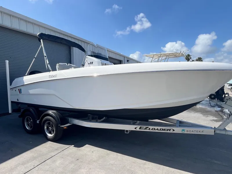Slide: The Image of 2022 Wellcraft 202 Fisherman boat on trailer, parked outdoors under a clear blue sky. - 2