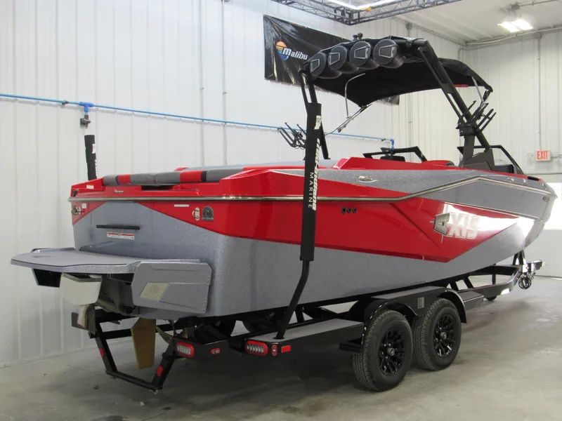 Slide: The Image of 2024 Axis T235 boat in red and gray, parked indoors on a trailer. - 3