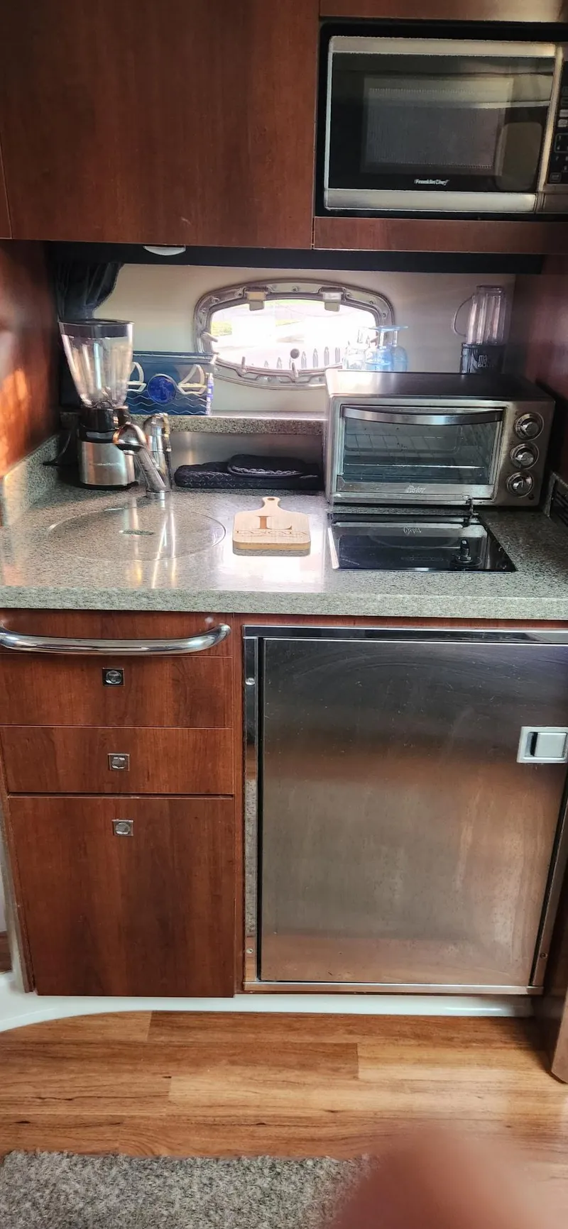 Slide: The Image of 2014 Chaparral 330 Signature Cruiser kitchen with appliances and wooden cabinetry. - 11