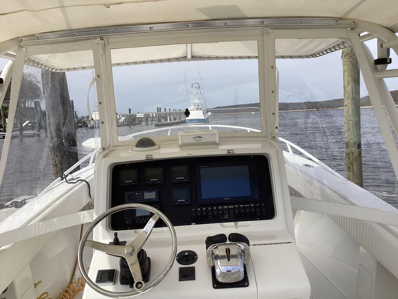 Slide: The Image of 2002 Jupiter 31 Cuddy boat helm with steering wheel and control panel, docked by the water. - 12