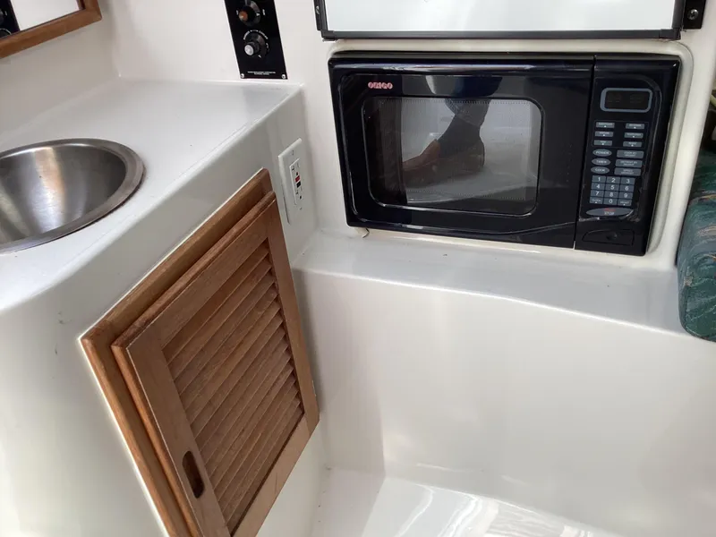Slide: The Image of 2002 Jupiter 31 Cuddy interior with microwave, sink, and wooden cabinet. - 15