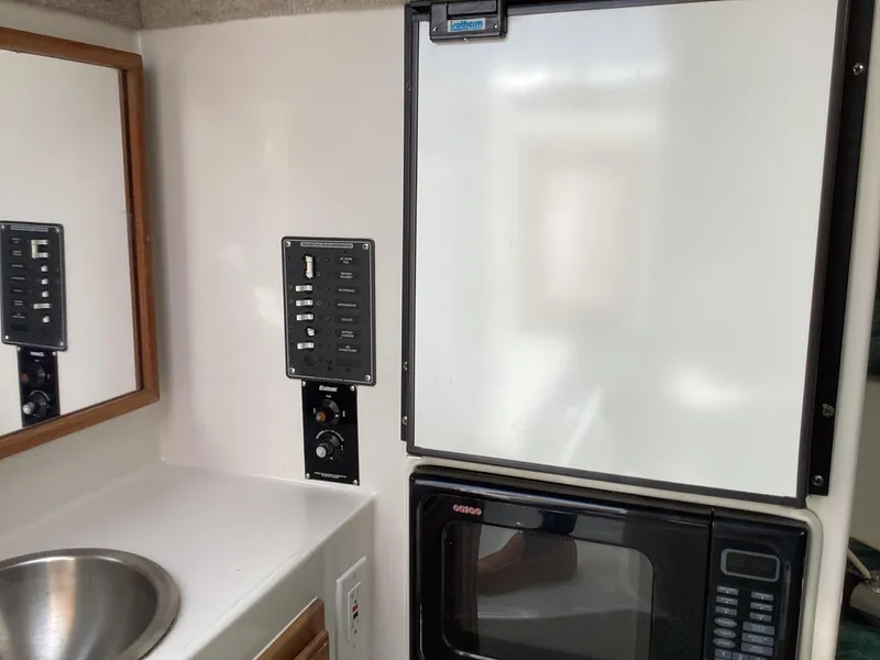 Slide: The Image of 2002 Jupiter 31 Cuddy interior with sink, control panel, fridge, and microwave. - 16