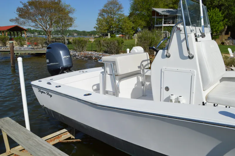 Slide: The Image of 2016 Layton Bay 22 boat docked by a scenic lakeside with trees and a house. - 12