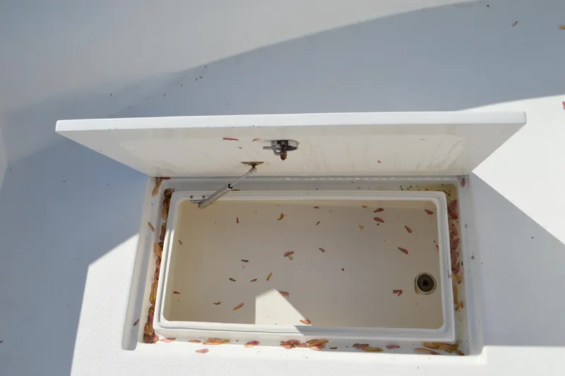 Slide: The Image of Open storage compartment on a 2016 Layton Bay 22 boat, with scattered debris inside. - 18