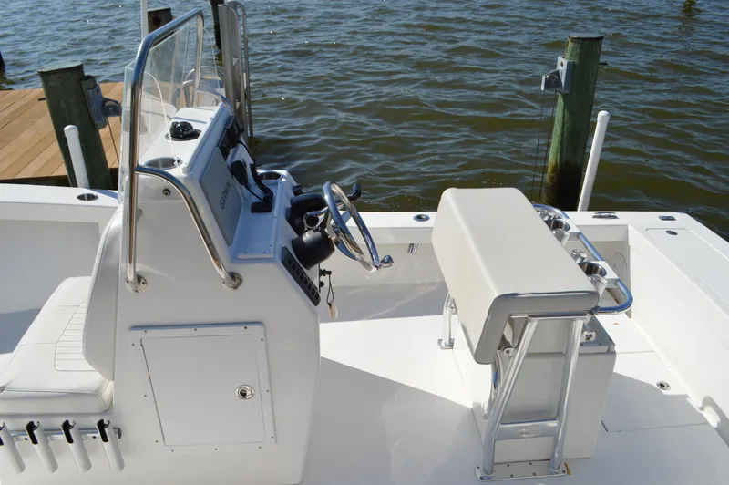 Slide: The Image of 2016 Layton Bay 22 boat interior with steering console and seating, docked by the water. - 19