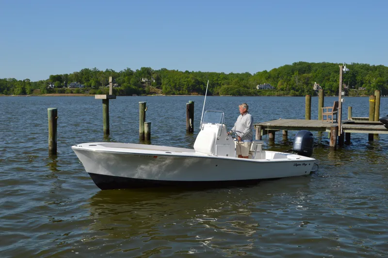 Slide: The Image of 2016 Layton Bay 22 boat on water near dock, clear sky, lush green background. - 2