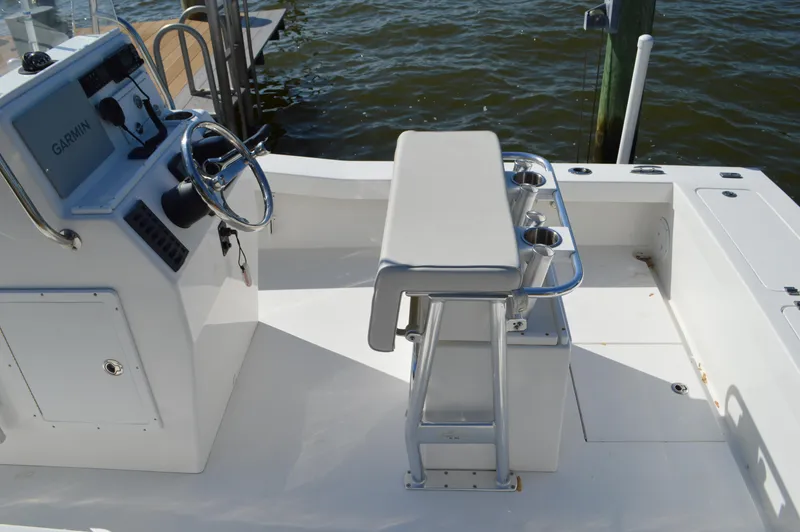 Slide: The Image of 2016 Layton Bay 22 boat cockpit with steering console and seating, docked by the water. - 24