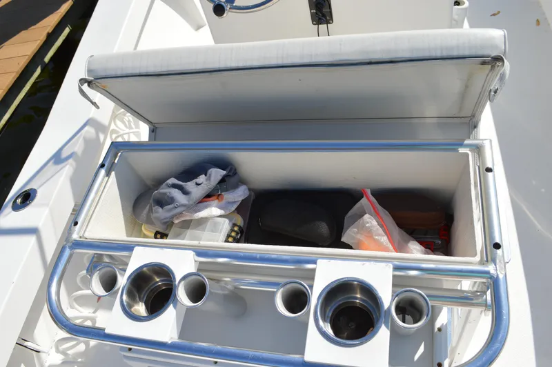 Slide: The Image of Open storage compartment on a 2016 Layton Bay 22 boat with cup holders and gear. - 29
