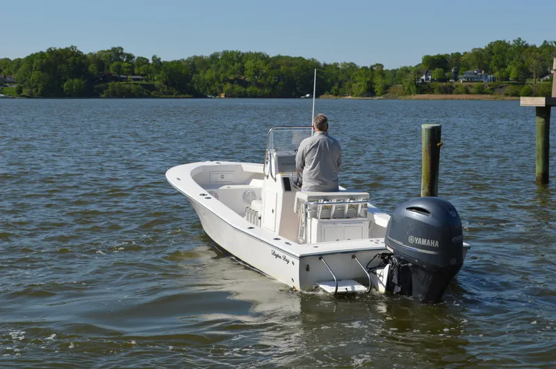 Slide: The Image of Man steering 2016 Layton Bay 22 boat on a calm lake with Yamaha motor. - 6
