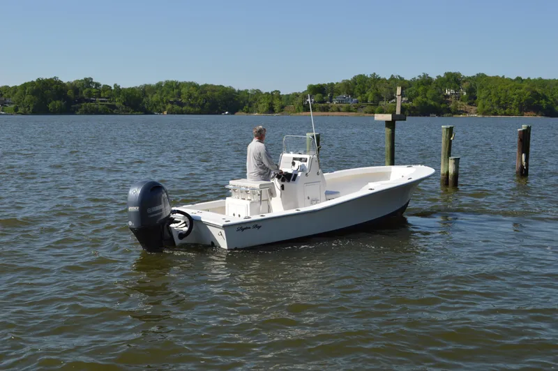 Slide: The Image of A 2016 Layton Bay 22 boat on a calm lake with a person steering. - 7