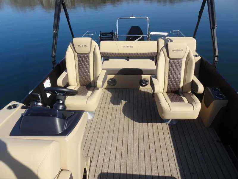 Slide: The Image of 2025 Harris Sunliner 250 boat interior with beige seating and sleek design on calm water. - 14