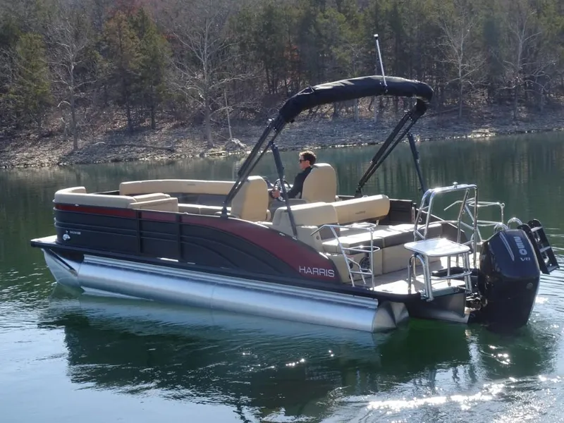 Slide: The Image of 2025 Harris Sunliner 250 pontoon boat on a calm lake, surrounded by trees. - 4