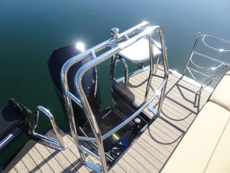 Slide: The Image of 2025 Harris Sunliner 250 boat deck with chrome railing and motor, on calm water. - 7