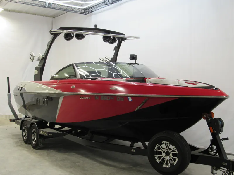 Slide: The Image of 2017 Malibu Wakesetter 25 LSV boat in a showroom, red and black design. - 1