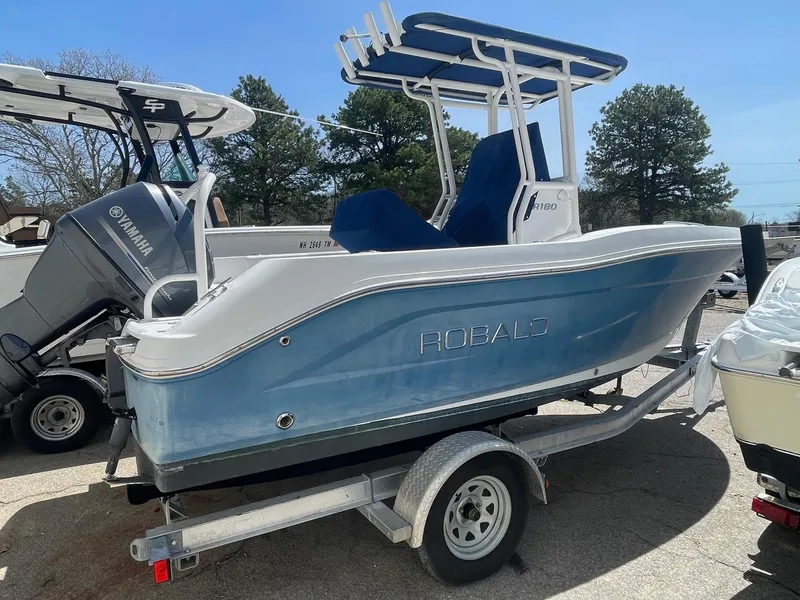 Slide: The Image of 2012 Robalo 180 CC boat on trailer, blue hull, Yamaha outboard, parked outdoors. - 4
