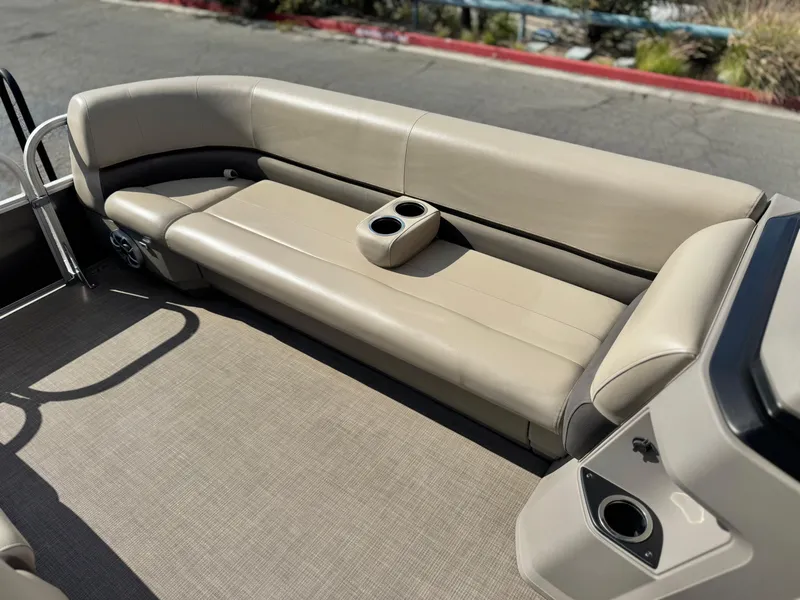 Slide: The Image of 2024 Sun Tracker Party Barge 18 DLX interior with beige seating and cup holders. - 10