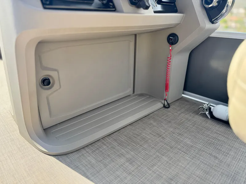 Slide: The Image of 2024 Sun Tracker Party Barge 18 DLX dashboard with storage compartment and safety lanyard. - 23