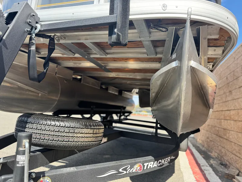 Slide: The Image of 2024 Sun Tracker Party Barge 18 DLX on trailer, showcasing pontoons and undercarriage. - 3