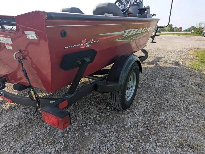Slide: The Image of 2024 Tracker Super Guide V-16 SC boat on a trailer, parked on gravel. - 5