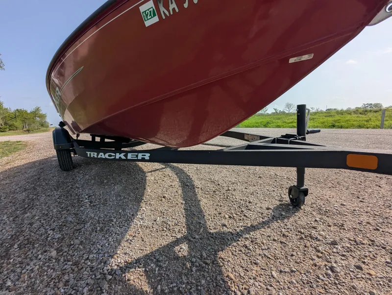 Slide: The Image of 2024 Tracker Super Guide V-16 SC boat on trailer, parked on gravel road. - 9