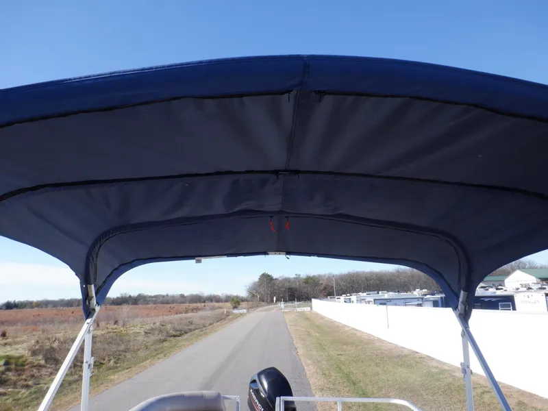 Slide: The Image of 2014 Sun Tracker Party Barge 24 DLX with blue canopy on a rural road. - 37