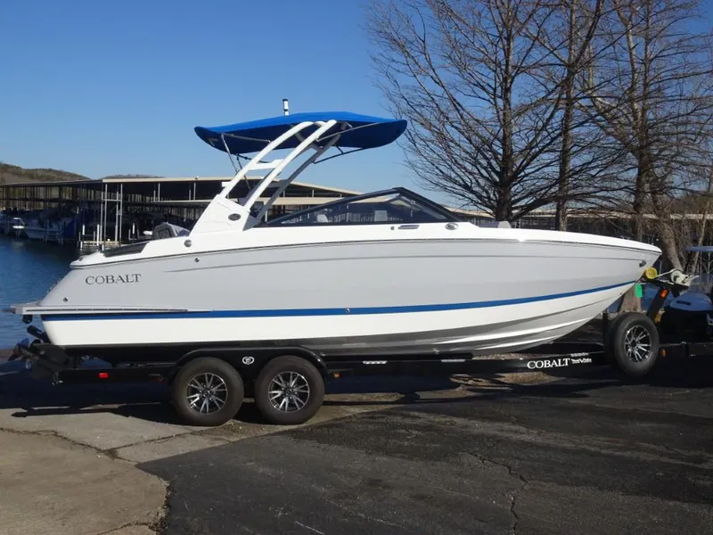 Slide: The Image of 2025 Cobalt R4 boat on trailer, white with blue accents, parked near marina. - 3