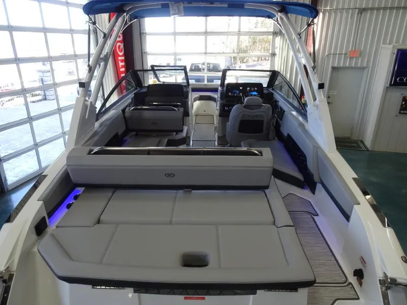 Slide: The Image of 2025 Cobalt R4 boat interior with spacious seating and modern dashboard in a showroom. - 6