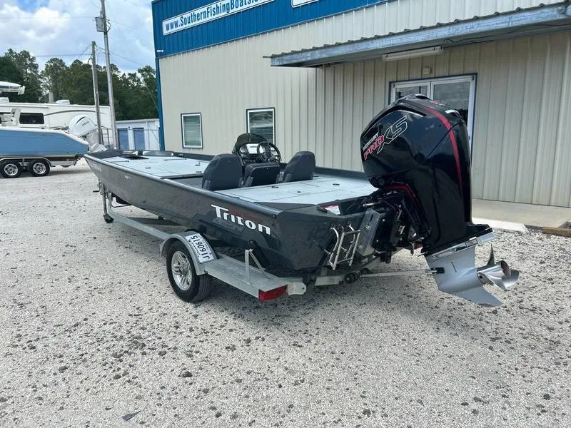 Slide: The Image of 2019 Triton 18 TX boat with trailer, parked outside a building. - 1
