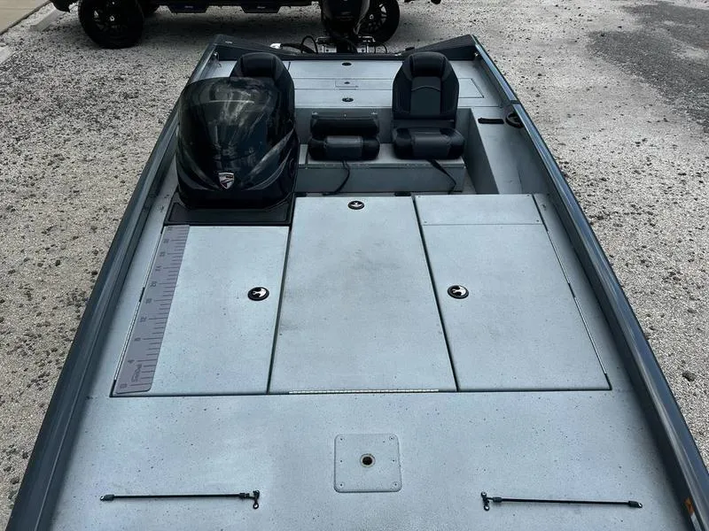 Slide: The Image of 2019 Triton 18 TX boat with dual seats and spacious deck, parked on gravel. - 12