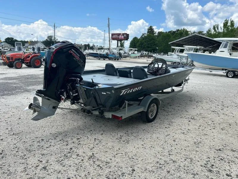 Slide: The Image of 2019 Triton 18 TX boat on trailer in outdoor lot, clear sky background. - 2