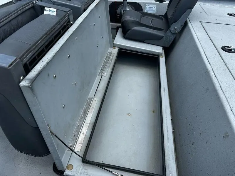 Slide: The Image of 2019 Triton 18 TX boat interior storage compartment with open lid and seating area. - 20