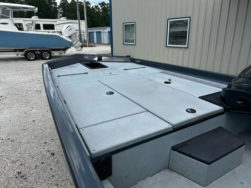 Slide: The Image of 2019 Triton 18 TX boat with spacious deck, parked near a building. - 6