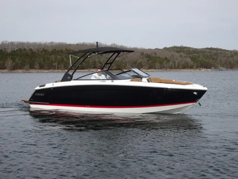 Slide: The Image of 2025 Cobalt R8 boat cruising on a calm lake with forested shoreline. - 1