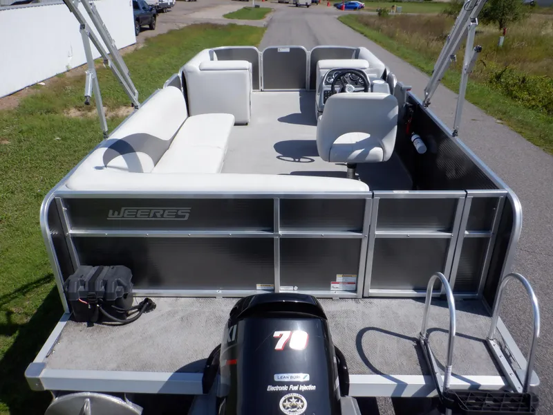 Slide: The Image of 2014 Weeres Cadet Cruise 200 pontoon boat with seating and steering console on a road. - 4