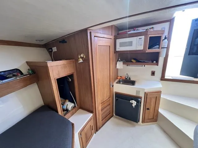 Slide: The Image of 1999 Albemarle 305 Express Fisherman cabin with kitchenette, storage, and seating area. - 13