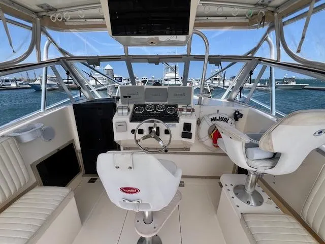 Slide: The Image of 1999 Albemarle 305 Express Fisherman boat cockpit with steering wheel and seating, docked at marina. - 7