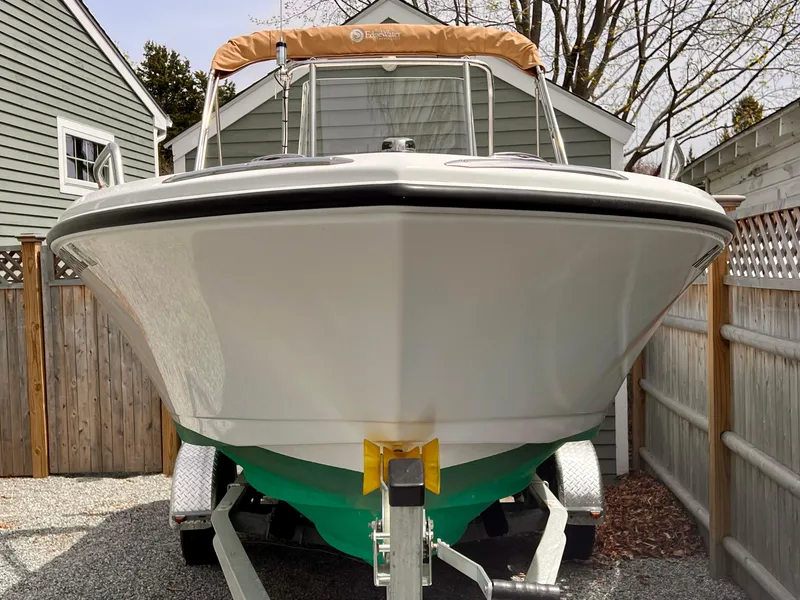 Slide: The Image of 2023 Edgewater 170CC boat on trailer, parked in a driveway with wooden fencing. - 1