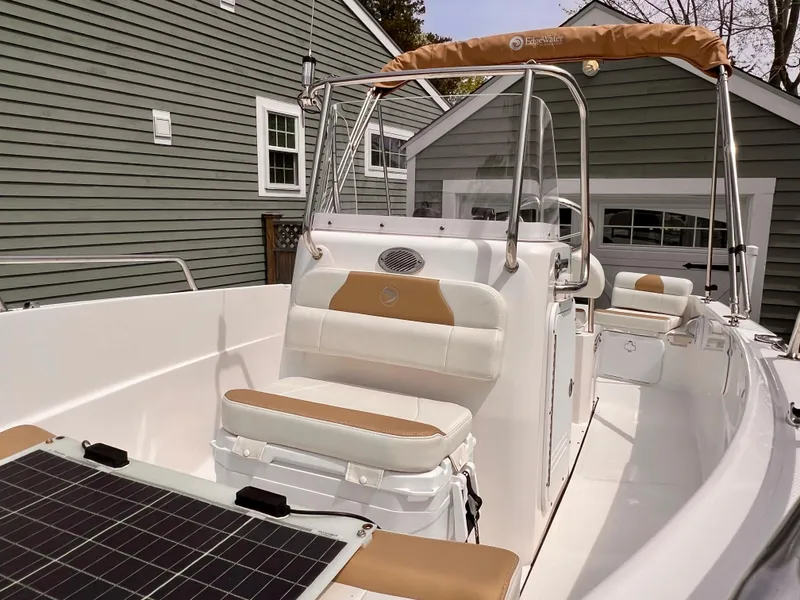 Slide: The Image of 2023 Edgewater 170CC boat with tan and white seating, parked near gray buildings. - 12