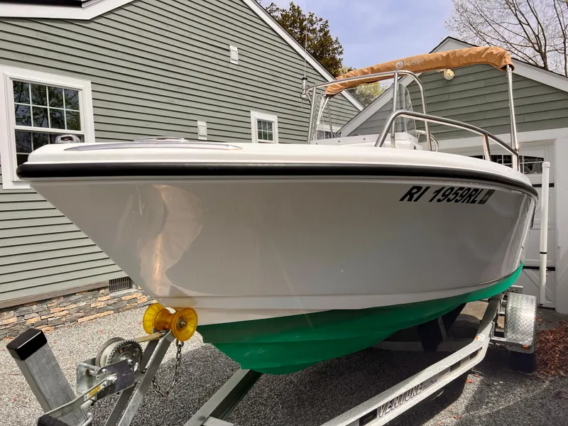 Slide: The Image of 2023 Edgewater 170CC boat on trailer, parked beside a gray house. - 2