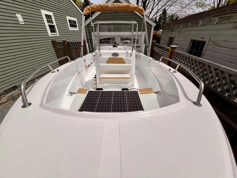 Slide: The Image of 2023 Edgewater 170CC boat with sleek design, white deck, and tan seating in a residential setting. - 3