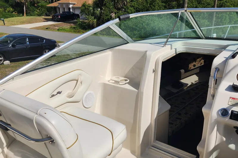 Slide: The Image of 2001 Sea Ray 215 boat interior with white seating and dashboard, parked near a residential area. - 9