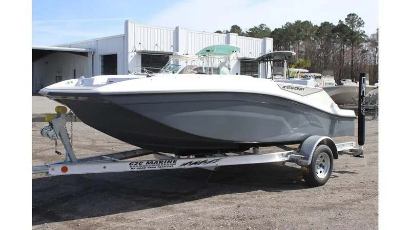 Slide: The Image of 2025 Starcraft SV 16 OB boat on trailer, parked outdoors near a marine facility. - 0